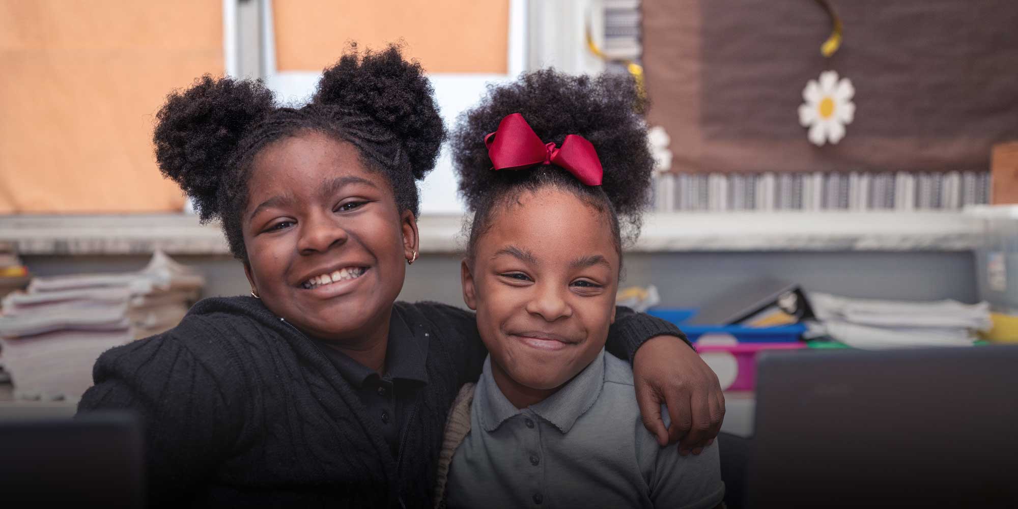 Two smiling Youngstown Academy students with their arms around each other.