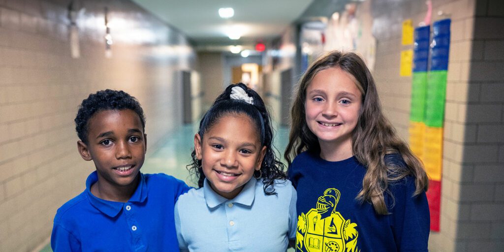 Group of smiling students with their arms around each other in the hallway